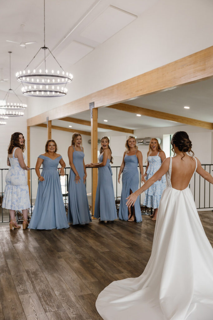 A bride showing off their outfit to their wedding party 