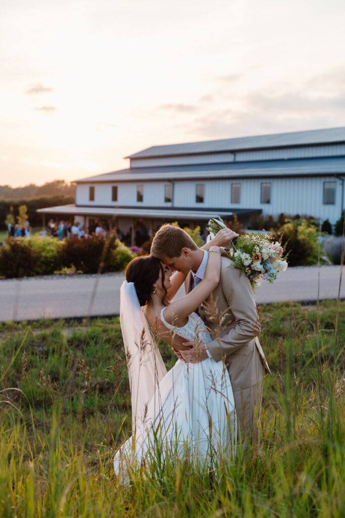 A newlywed couple hugging in tall grass 