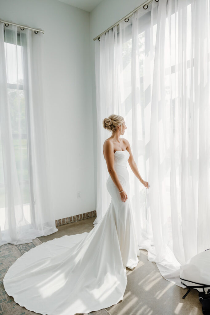 A person in a wedding dress looking out of a window 