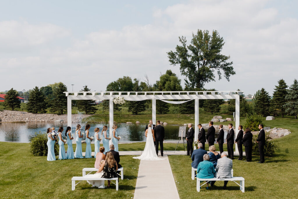 A view of a small wedding ceremony in front of a lake 