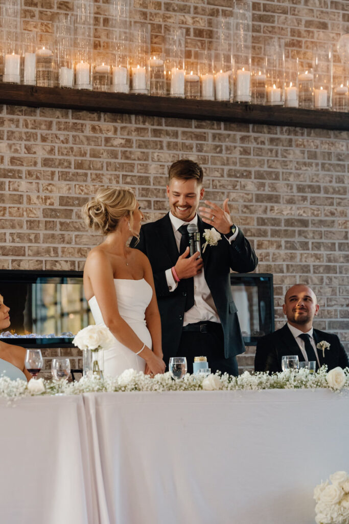 A wedding couple standing up and giving a speech at their reception 