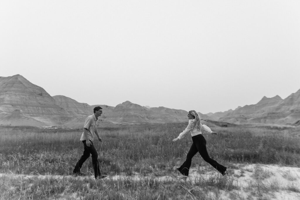 Black and white photo of a couple running towards each other in a field 