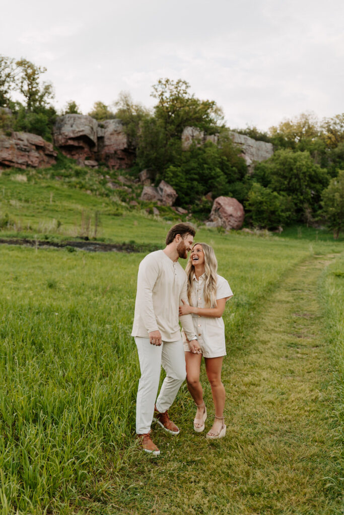 A couple holding hands and laughing together in a field 