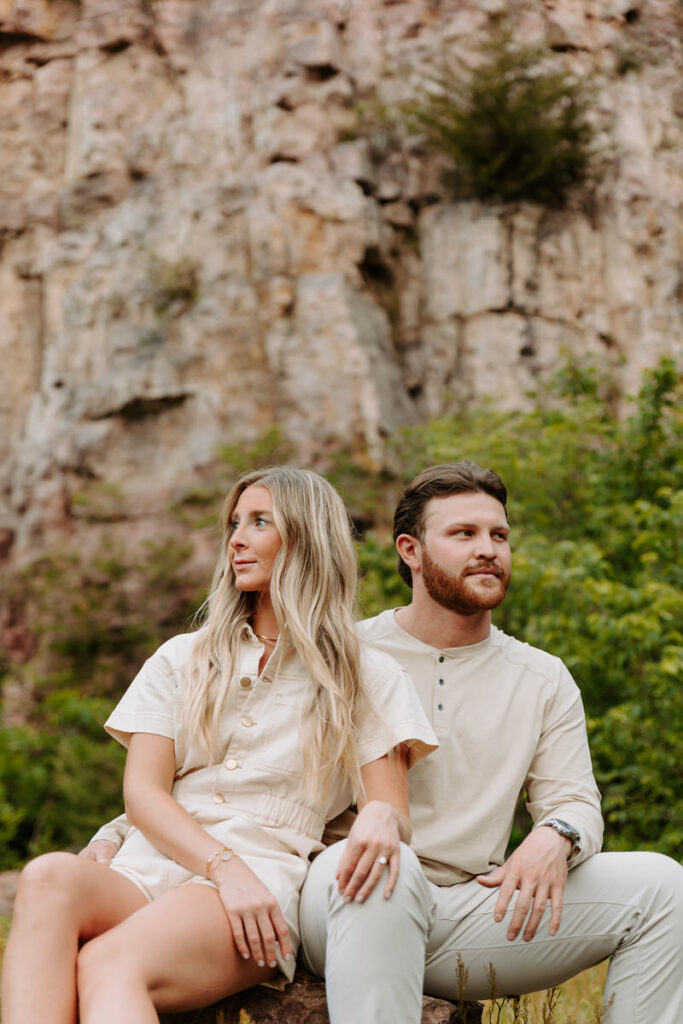 A couple sitting in a mountain area together with their arms around each other 
