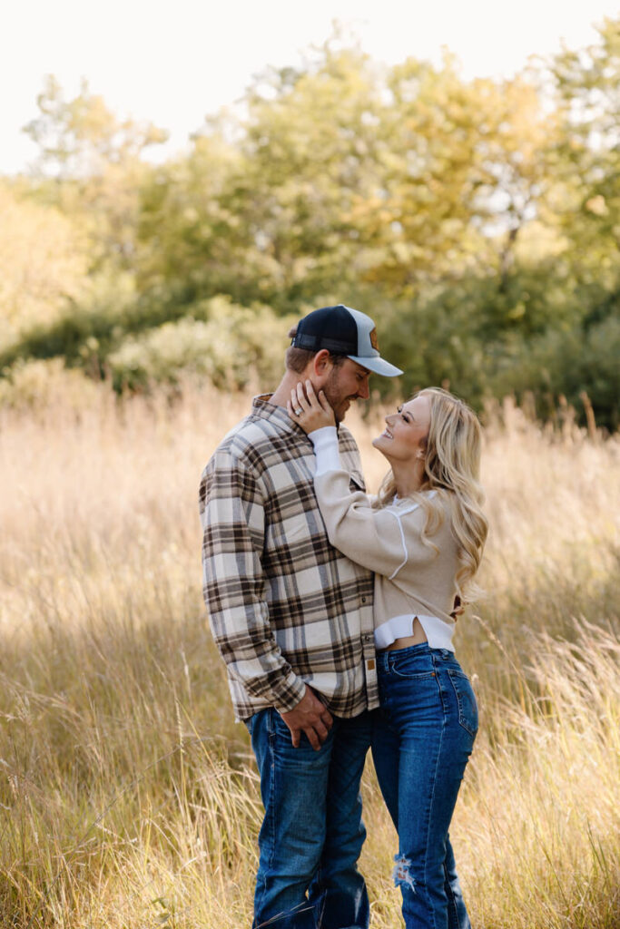 A couple standing close together as one reaches towards the other's face 