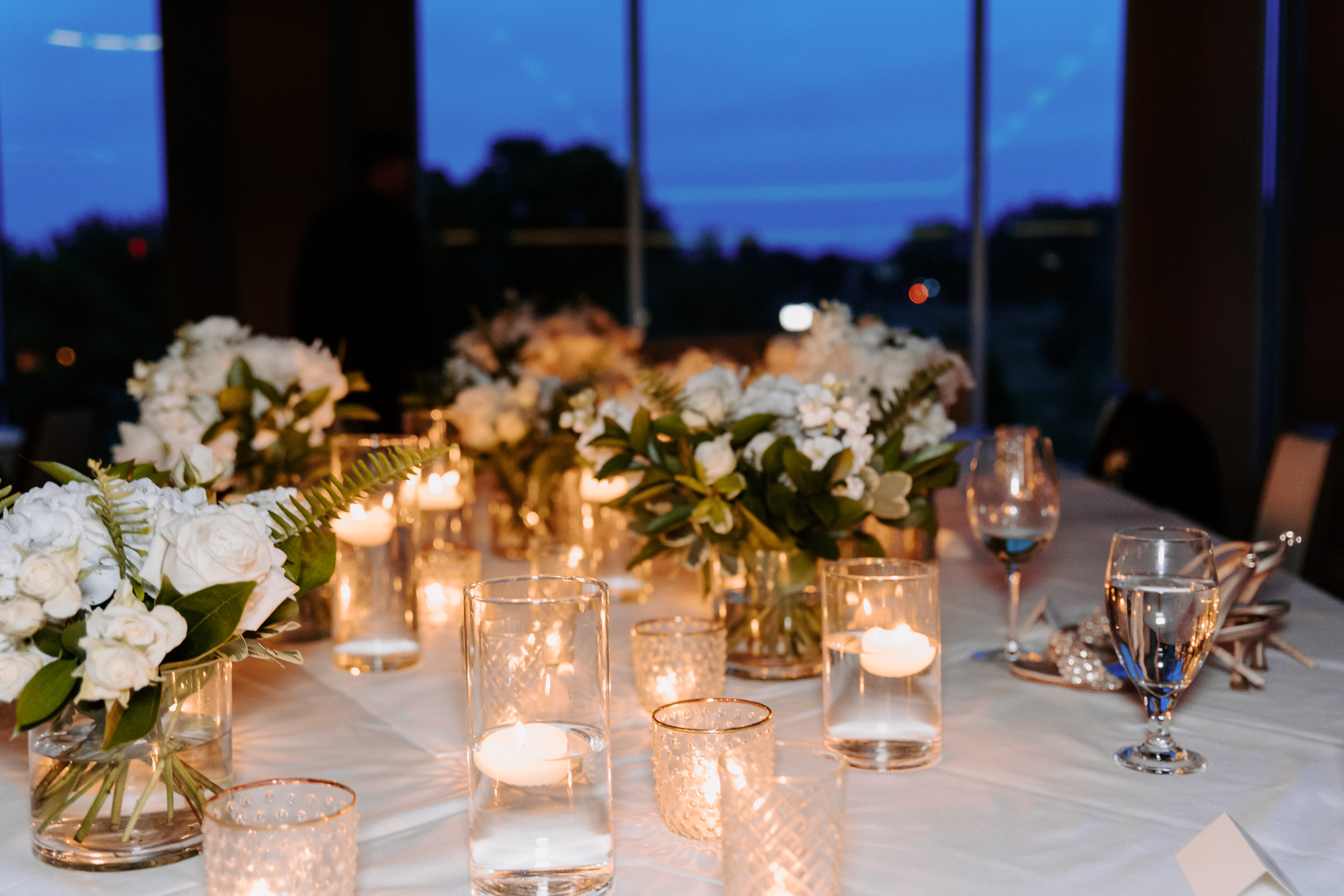 A wedding reception table set with small flower arrangements and candles