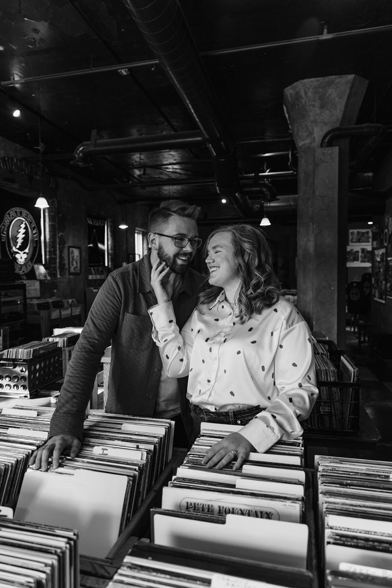 A photo showing how to prepare for engagement photos with a couple standing in a record shop looking at each other