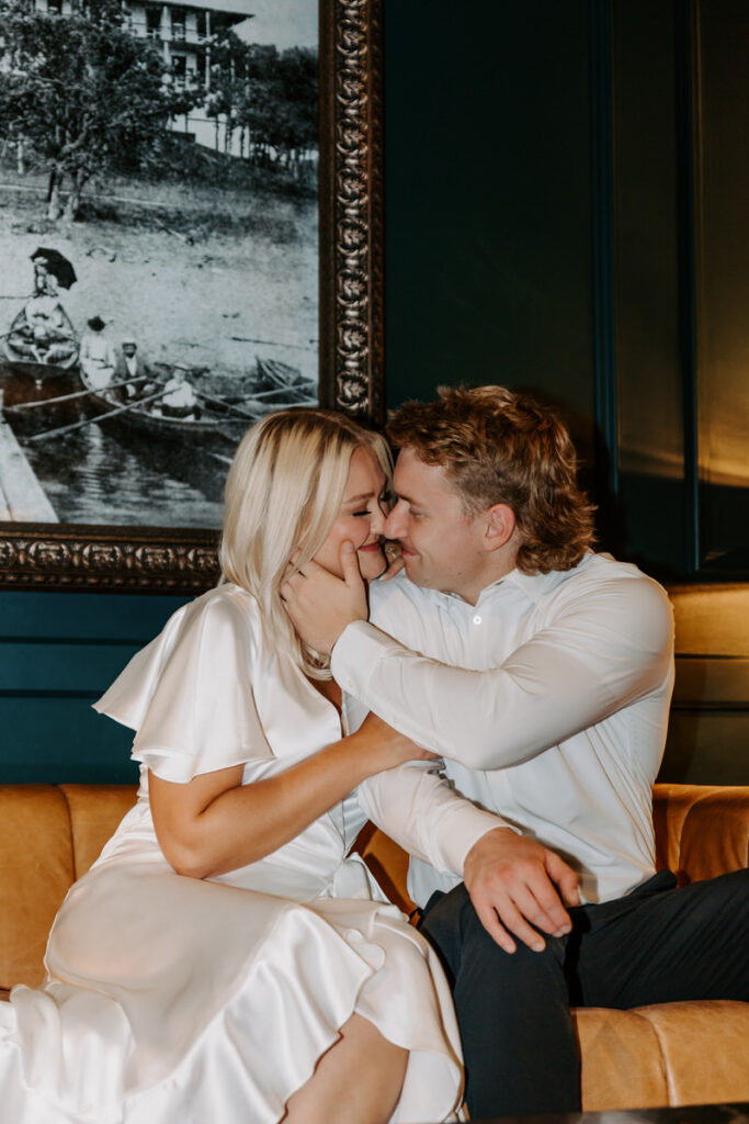 A couple sitting on a couch together about to kiss 