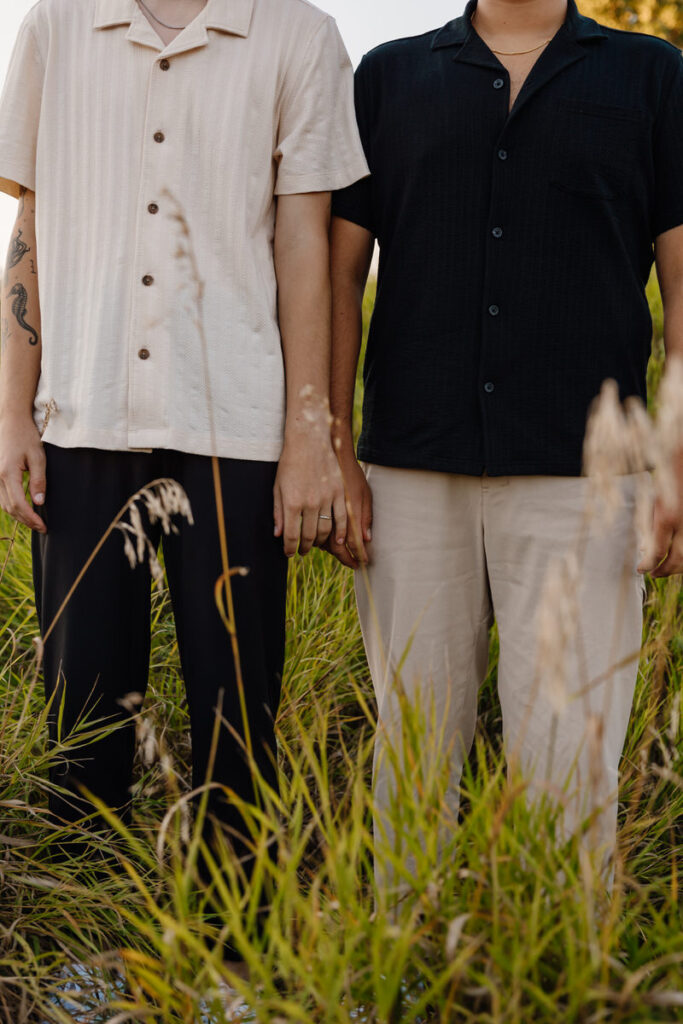 Close up of two people standing next together showing off an engagement ring 