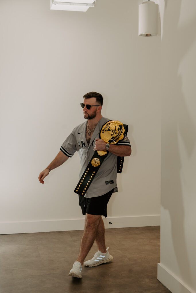 A person walking around a corner with a wresting belt over his shoulder 