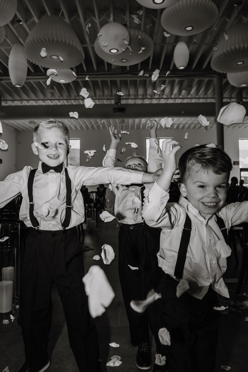 Young boys in suits smiling and throwing up flower petals