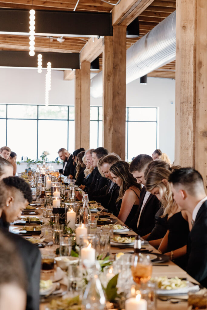 Wedding guests bowing their heads at a wedding reception 