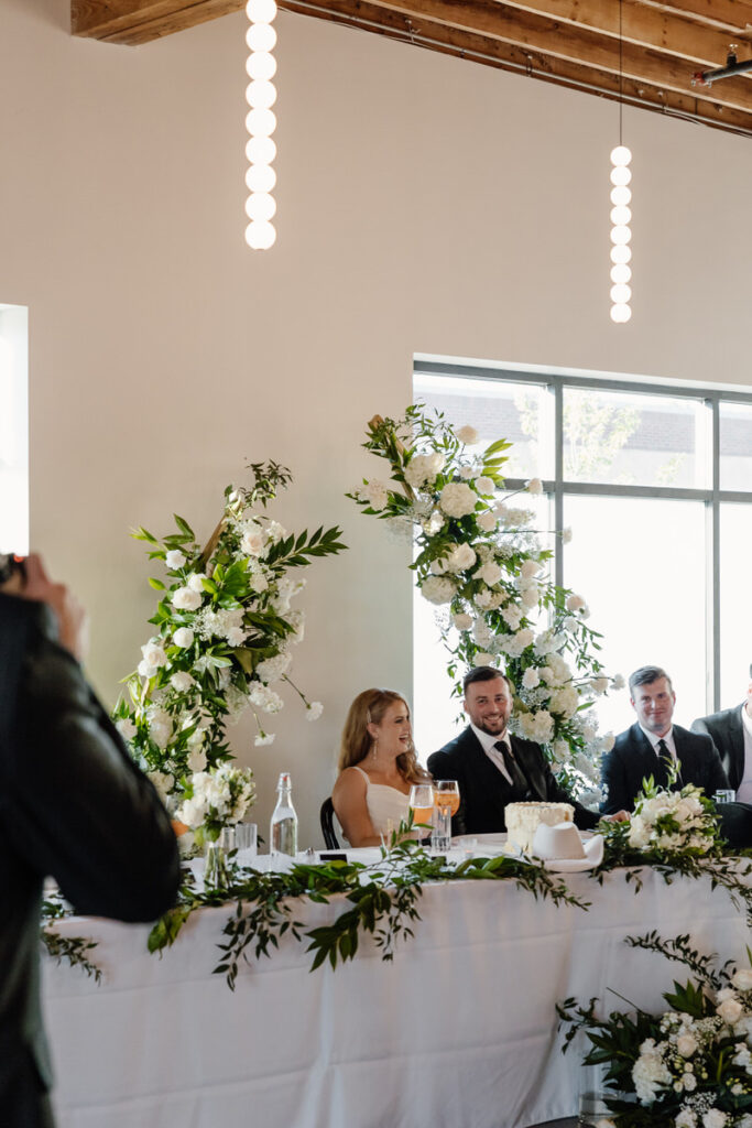 Newlyweds laughing and sitting at a reception table 