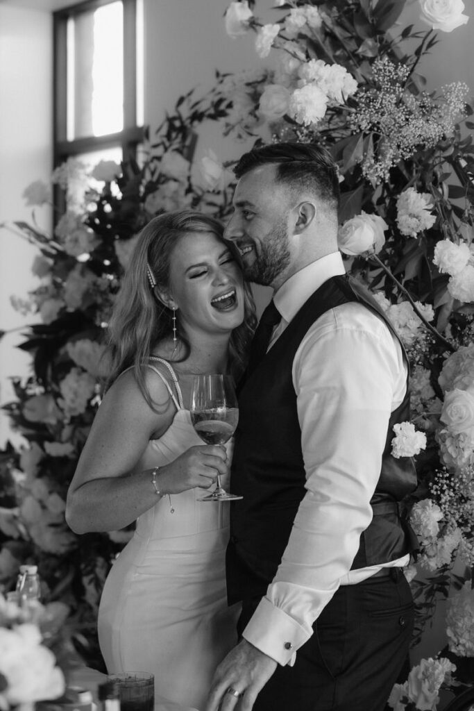 A newlywed couple hugging and laughing together at their reception 